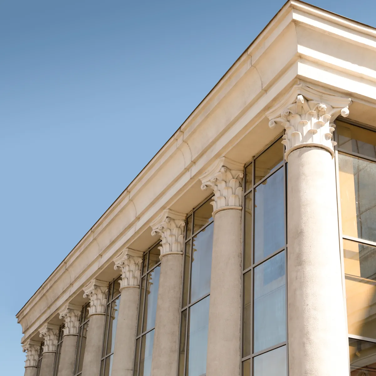 The columned facade of a bank building against a blue sky