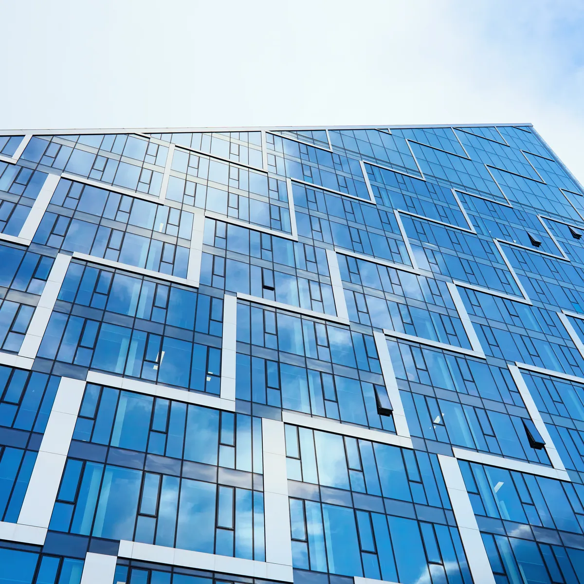 A glass office tower rising against a clear blue sky