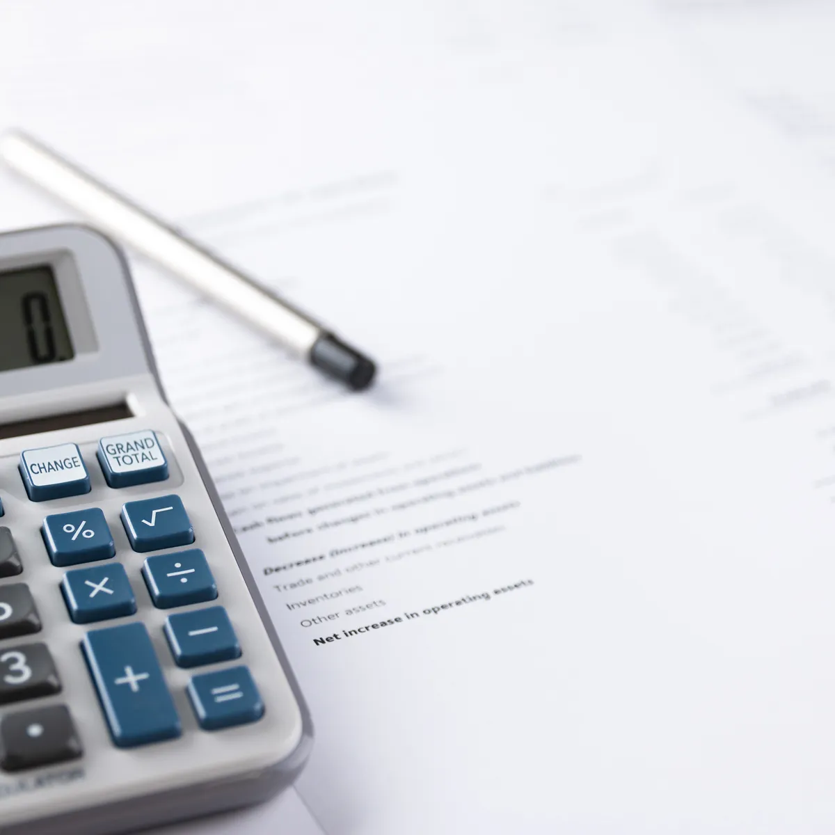 A calculator and pen resting on a printed financial statement