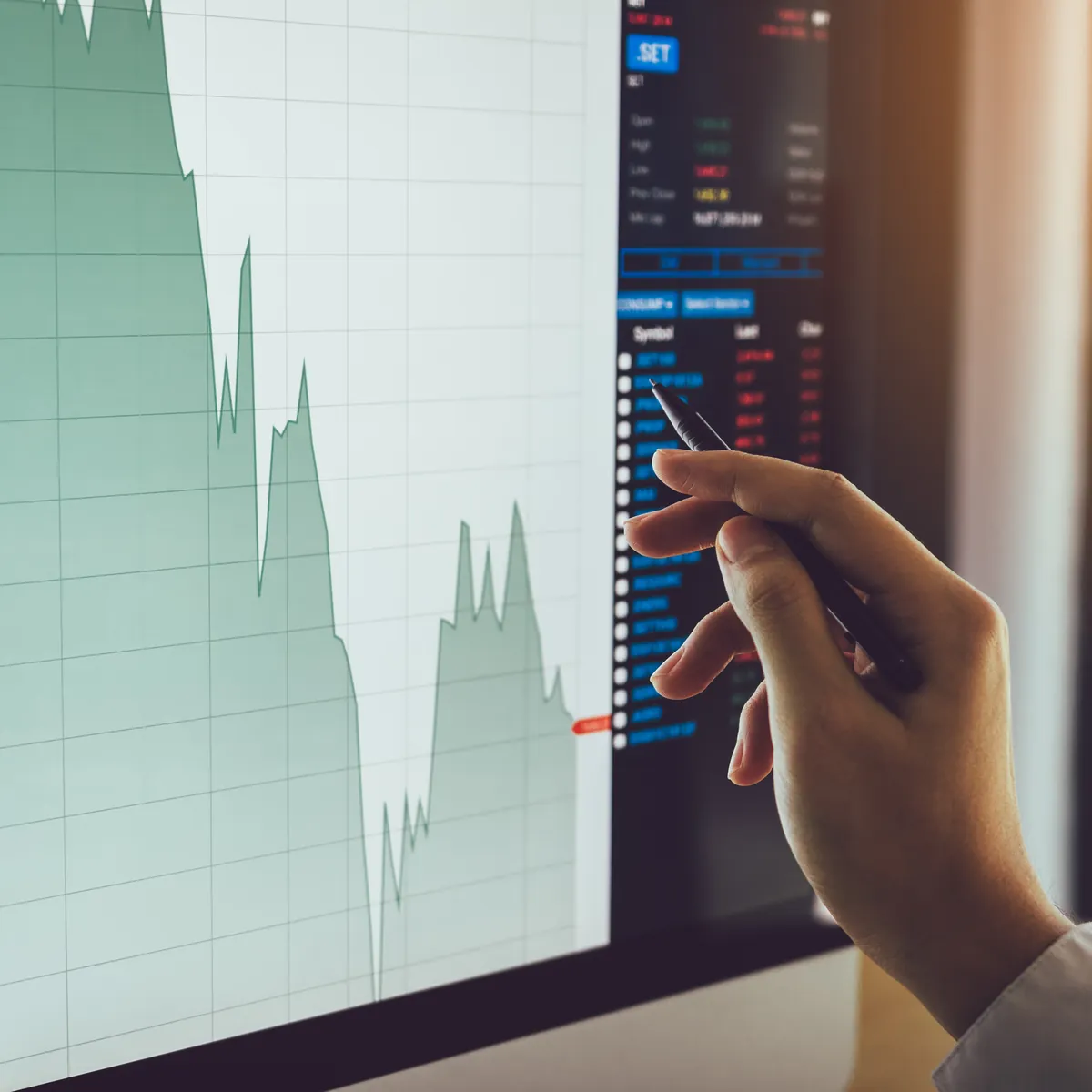 A hand tracing a financial data chart on a screen