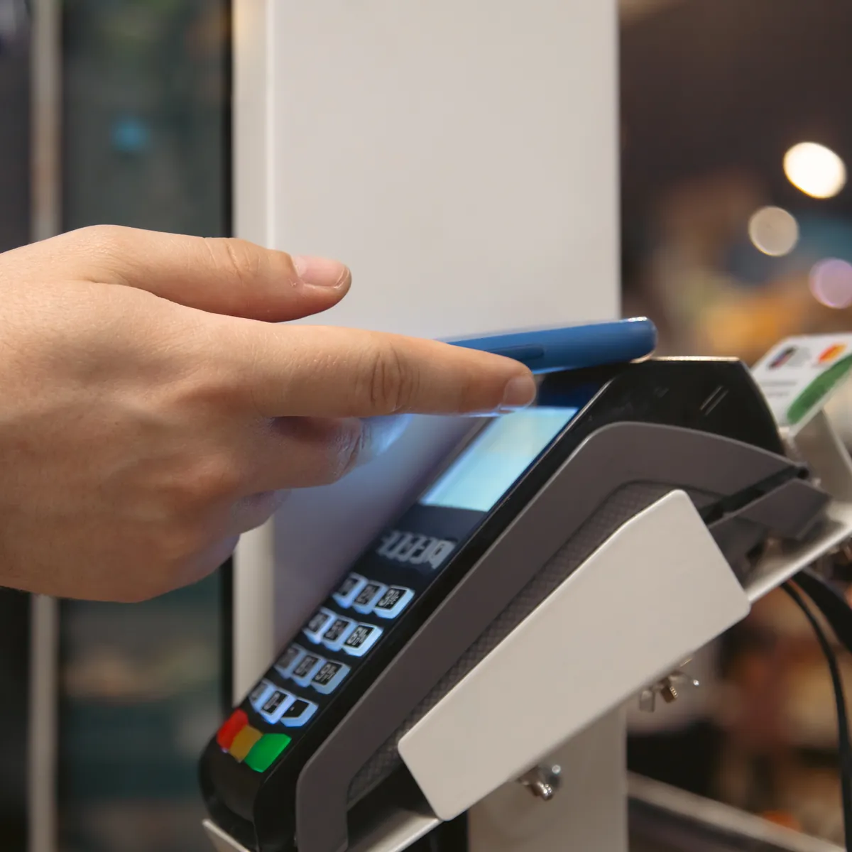 A customer paying by phone at a card terminal in a cafe