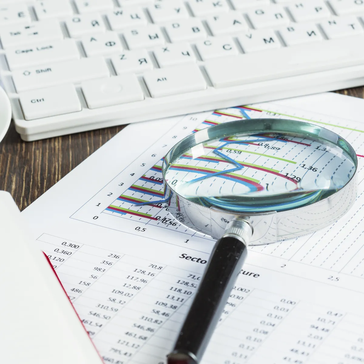 A magnifying glass held over a printed spreadsheet