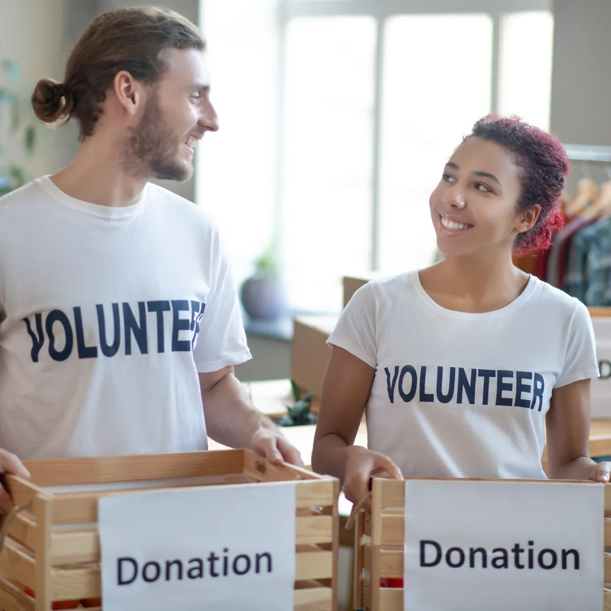 Volunteers carrying donation boxes in a bright room
