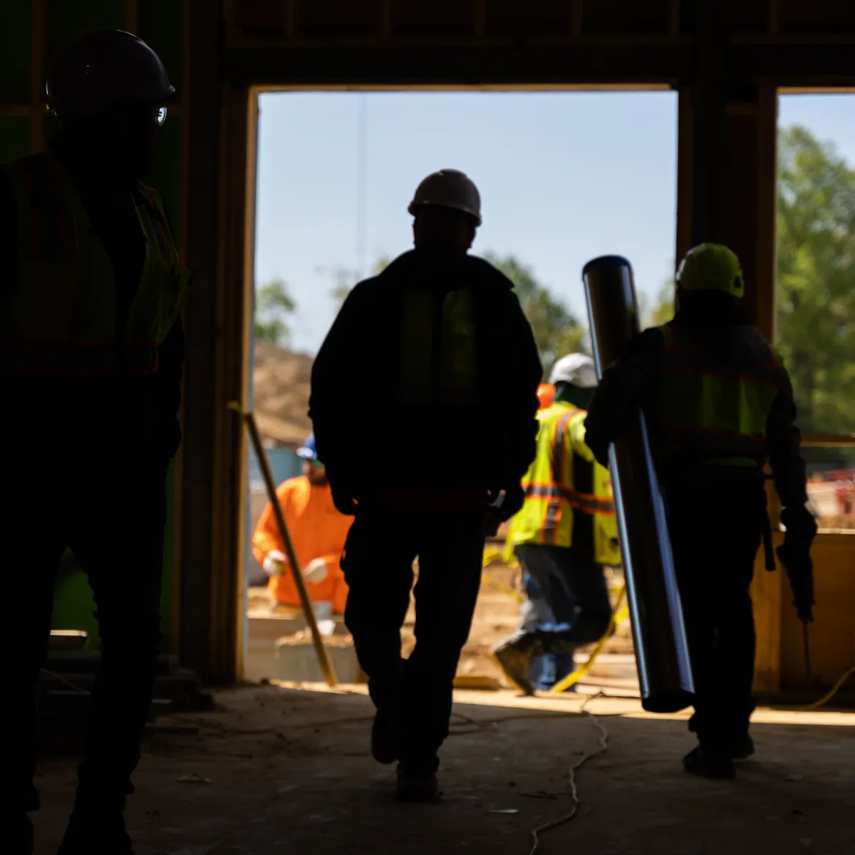 Construction workers silhouetted in the doorway of a building under construction