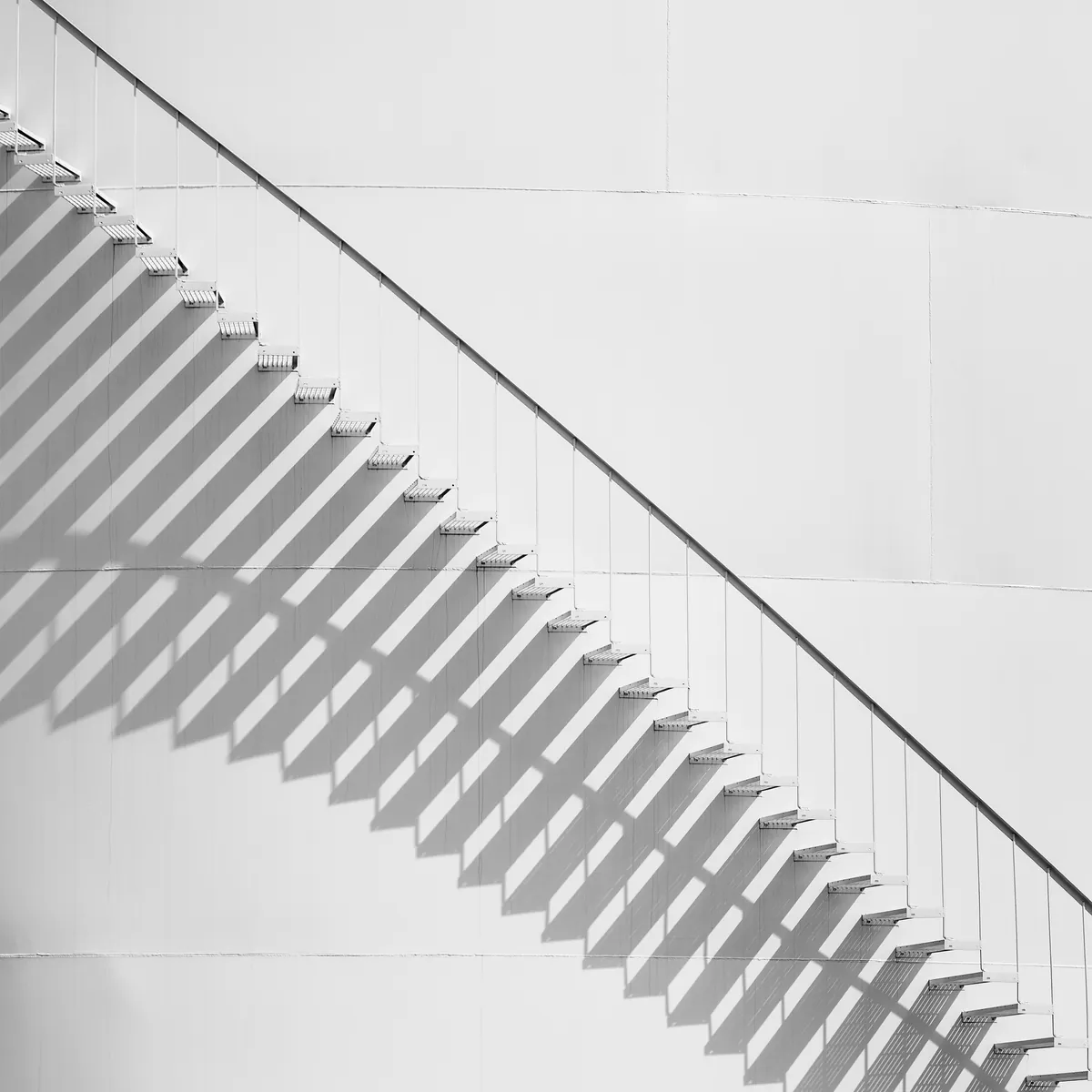 A staircase casting a rising diagonal of light and shadow
